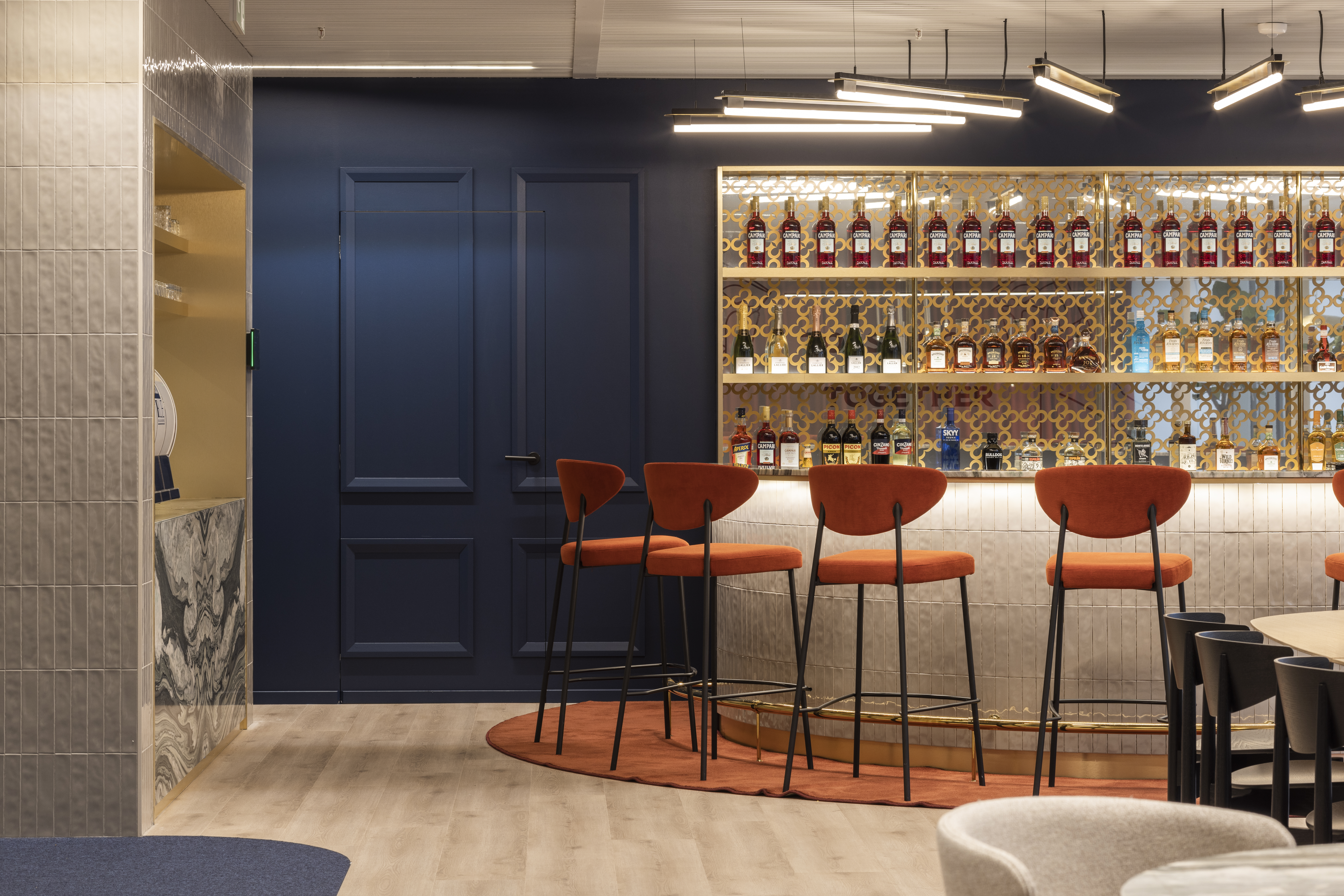 The bar is the focal point of the space with reddish-orange bar stools prominent all around.