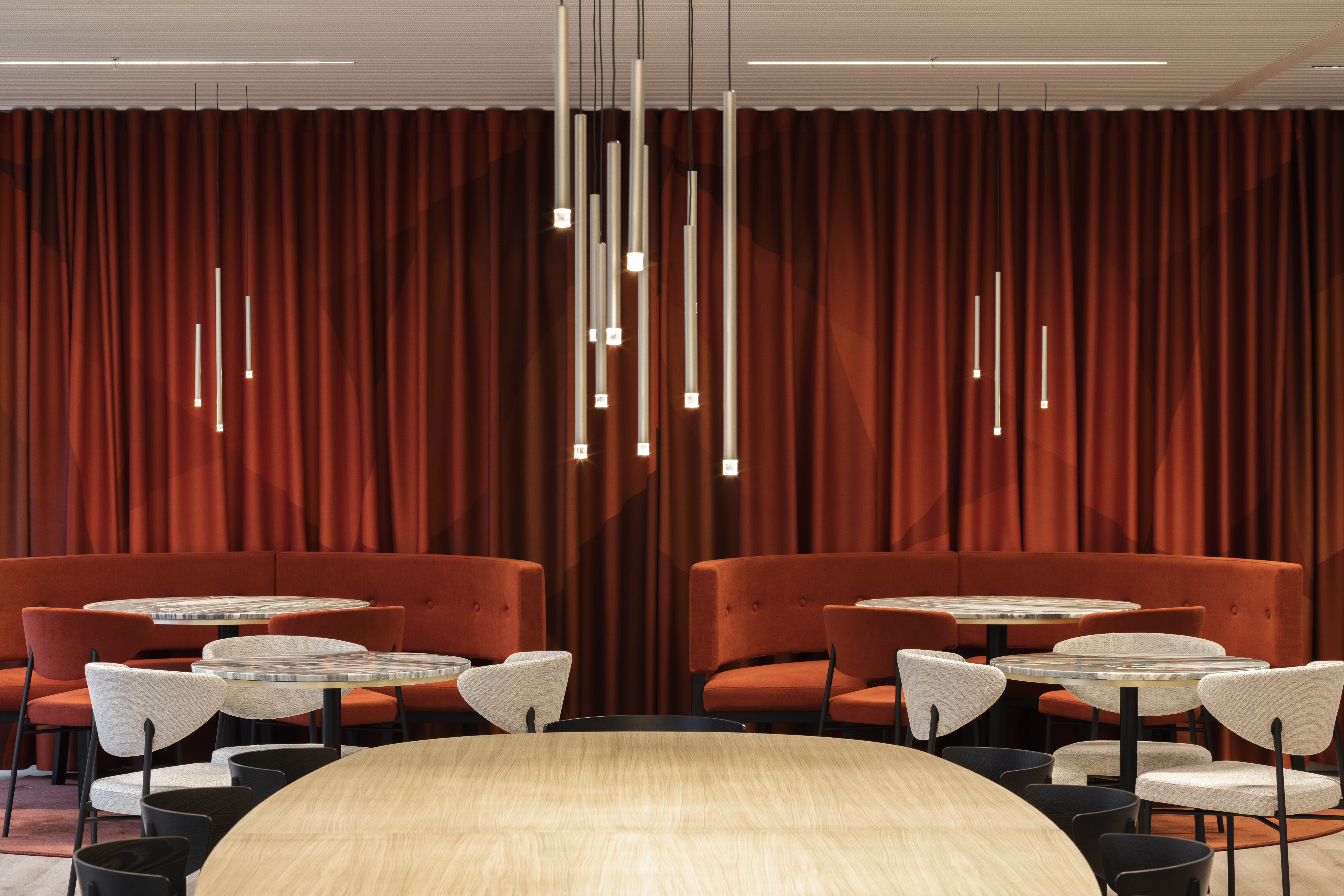 Cylindrical lights hang over the rich red booths of the workspace.